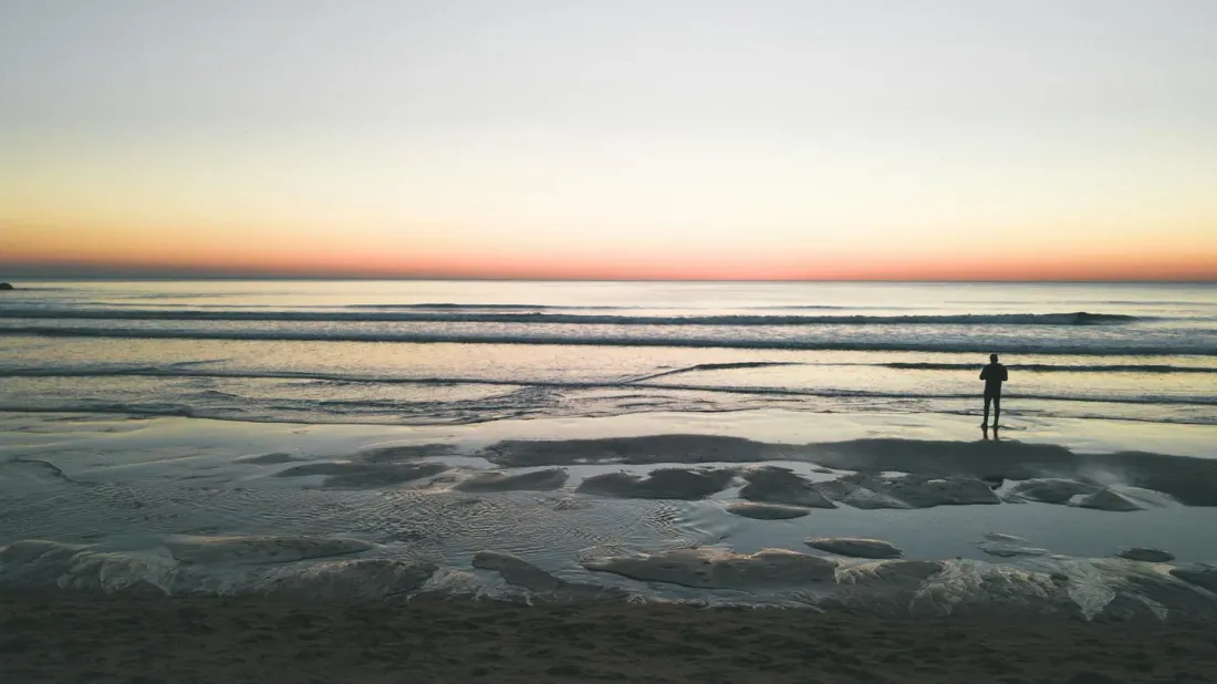 Silhouette of a person standing on a beach at sunset