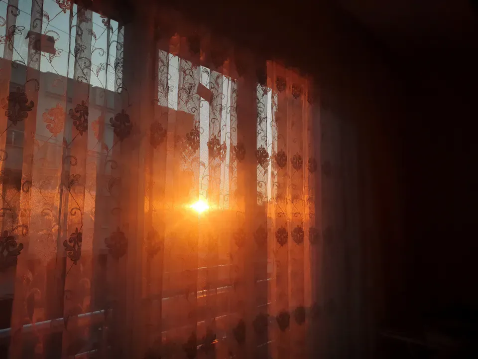 Warm light filtering through curtains into a quiet room