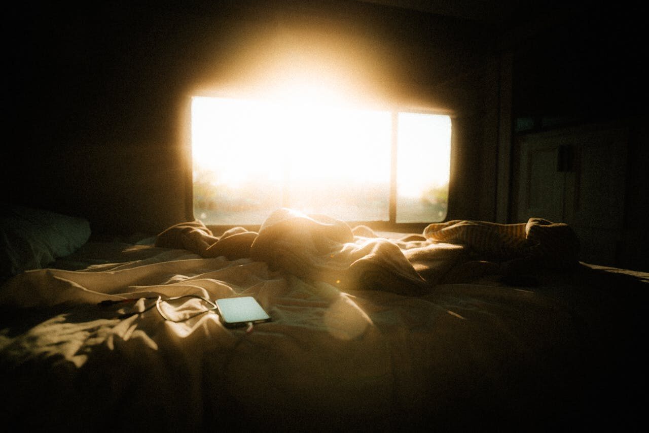 Sunlight falling softly on an unmade bed in a quiet room