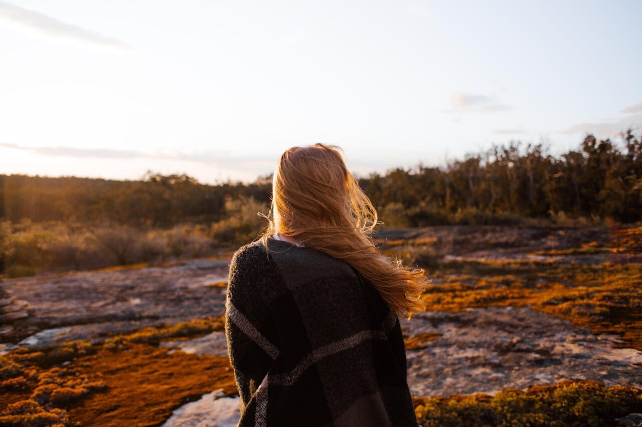 Person wrapping themselves in a cosy shawl, looking out at nature