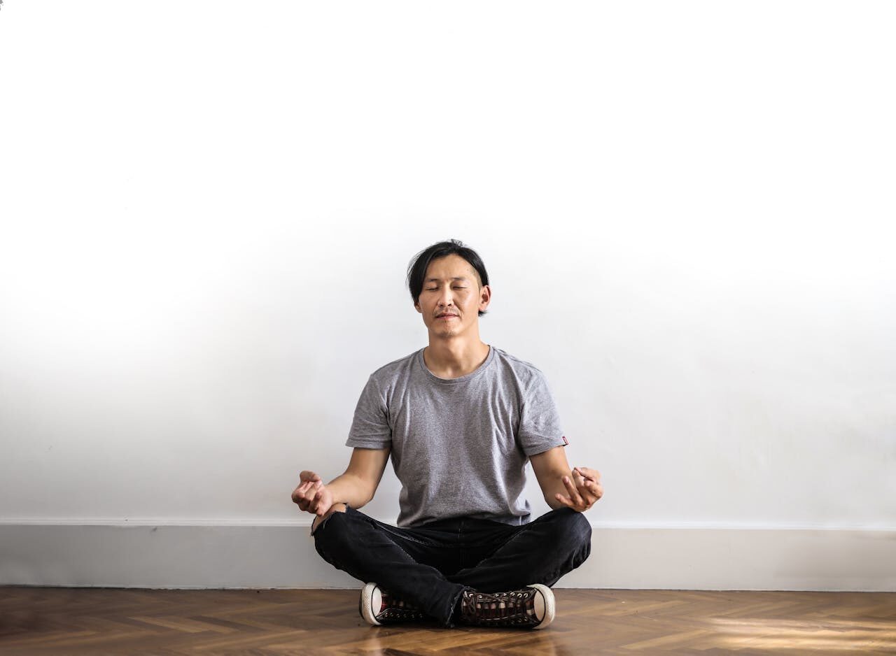 Person sitting cross-legged on a wooden floor in soft morning light